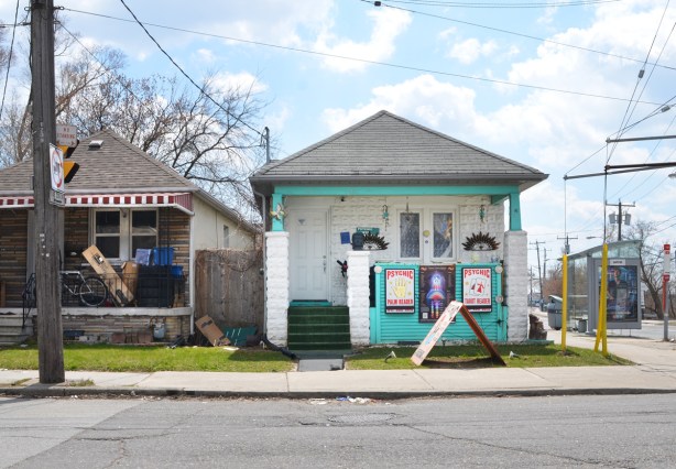 a little white house with teal or turquoise trim, with signs advertising business of a psychic 