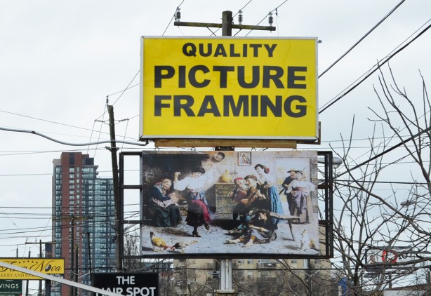 sign in front of a framing store, epty frame on top and an old faded picture on the bottom 
