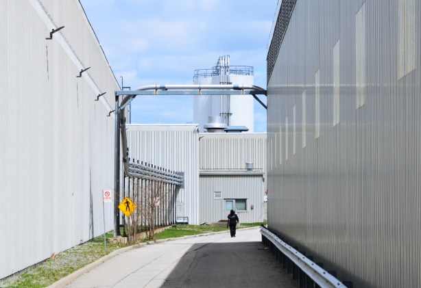 a security guard walks down a road between two white metal buildings