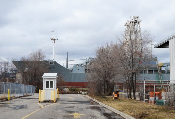 ship parked in channel, beside an empty parking lot with a small booth for attendant of parking lot