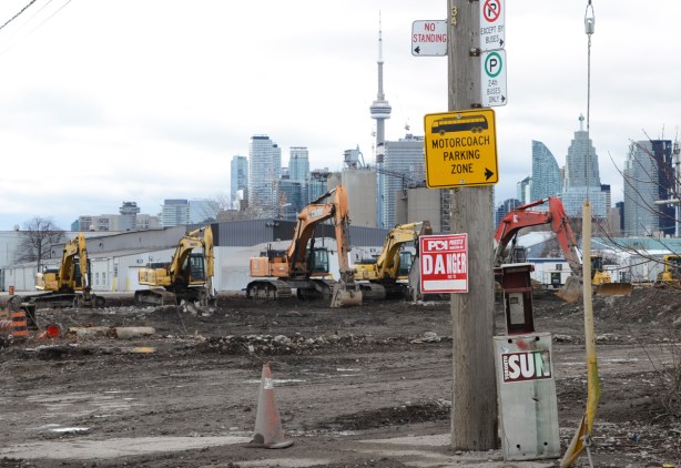 construction, signs on a wood pole, Toronto skyline in the background