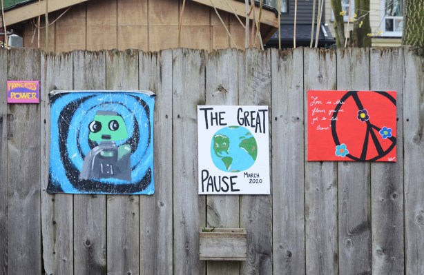 paintings on a fence including one that says the great pause.