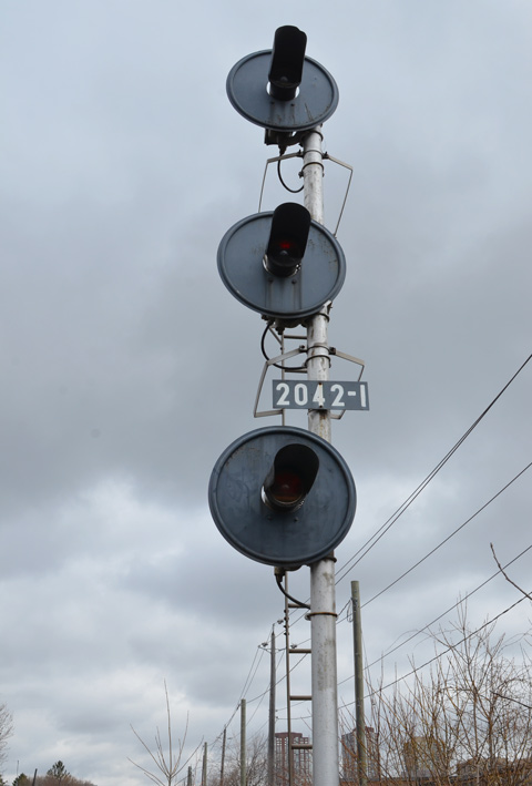 a set of three railway lights at 2042-1 pole, lights are arranged vertically, one on top of the other 