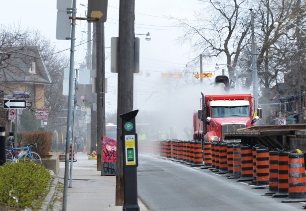 a red truck in the middle of Broadview Ave as TTC streetcar tracks are being removed, lots of dust. 