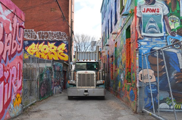 a large semi truck is parked in Graffiti Alley and is taking up the whole width of the lane