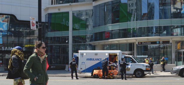 ambulance with paramedics talking to a man who is sitting in the ambulance, at Yonge and Dundas in front of the Easton Centre 