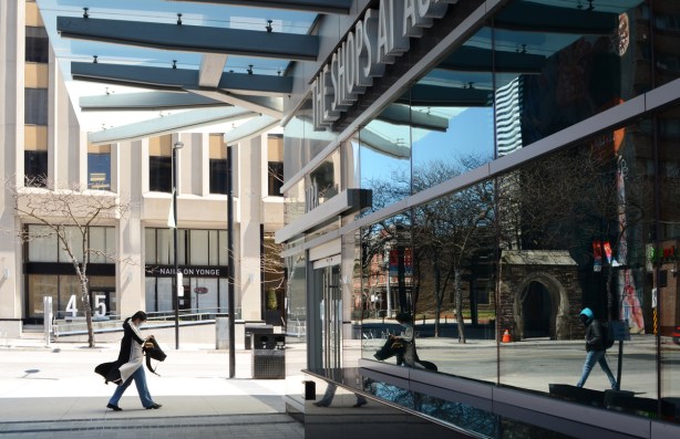 reflections in a large window on Yonge Street, a woman walks towards the window, the reflections of a man walking the other way are in the window 