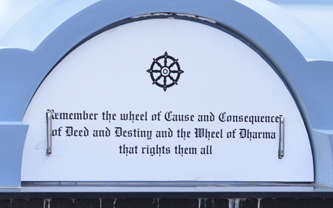 part of the base of a column with words that say remember the wheel of cause and consequence of deed and destiny and the wheel of dharma that rights them all 