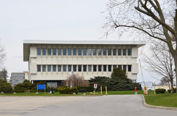 three storey white concrete building with the width of the floors increasing as you go upwards 
