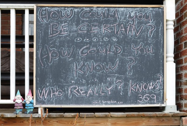two small gnomes stand beside a chalkboard on a porch with words on it that say 