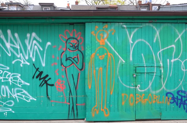 seafoam green colour garage door with graffiti drawings of people, dobgoblin, 