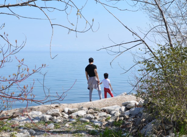 father and child standing on rocks at the shore of Lake Ontario 