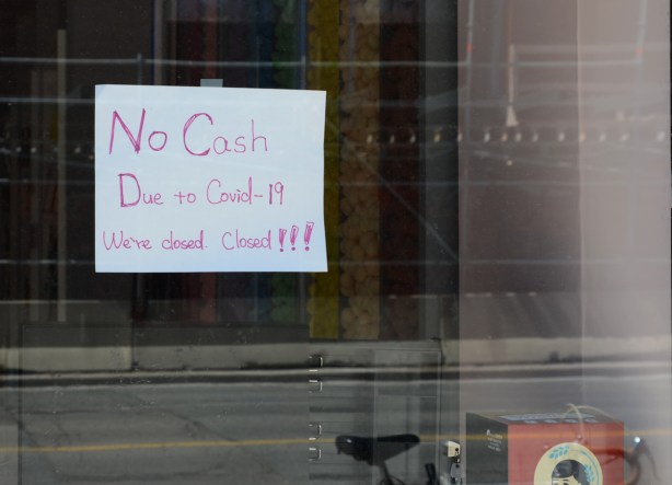 hand written sign in window of store, no cash, due to covid-19 we are closed