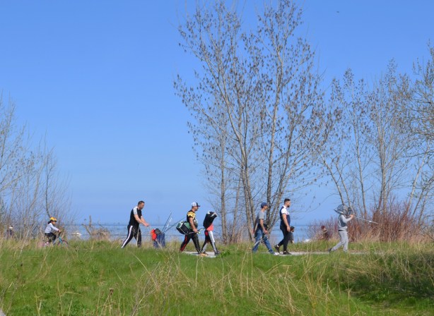 people walking on a trail in Tommy Thompson Park, early spring, trees just starting to form leaves 