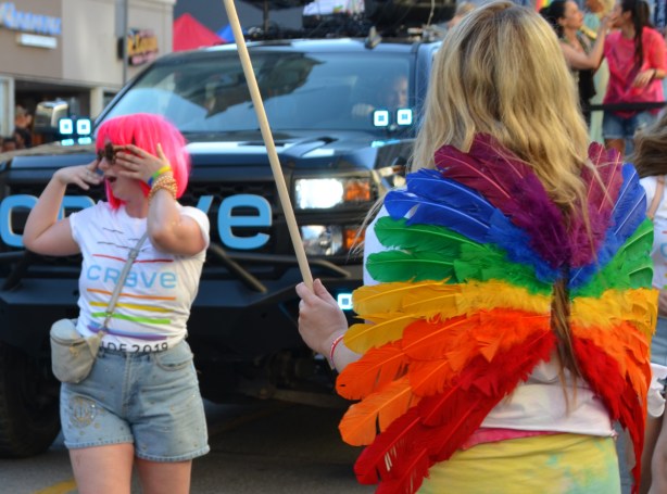 Pride parade, rainbow wings, dancing woman