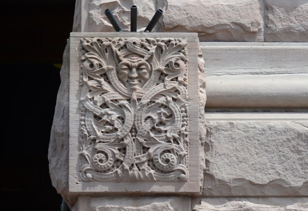 a man's face with what seems like horns from his head, a carving in stone