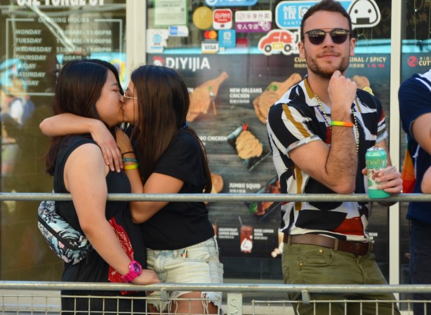 two women kissing, on sidewalk, outside, pride