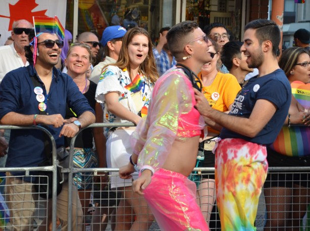 two people dancing, pride parade while spectators cheer 