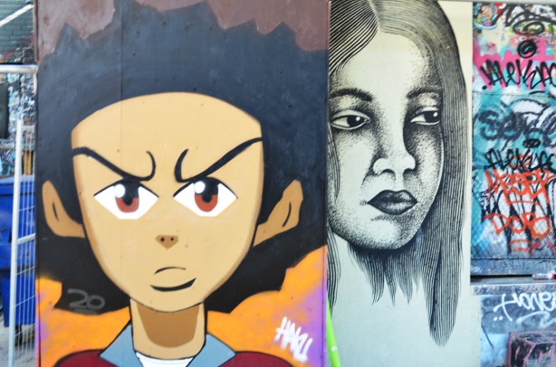 two faces in two murals adjacent to each other, one is of a young woman and the other is a boy