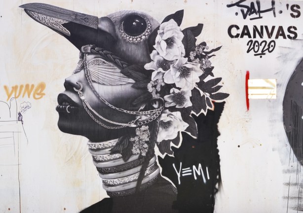 black and white and grey tones pasteup graffiti by yung of a woman with a hat that is a bird's head and large beak, many chains around her neck and her eyes are covered, lots of flowers covering the back of her head and neck