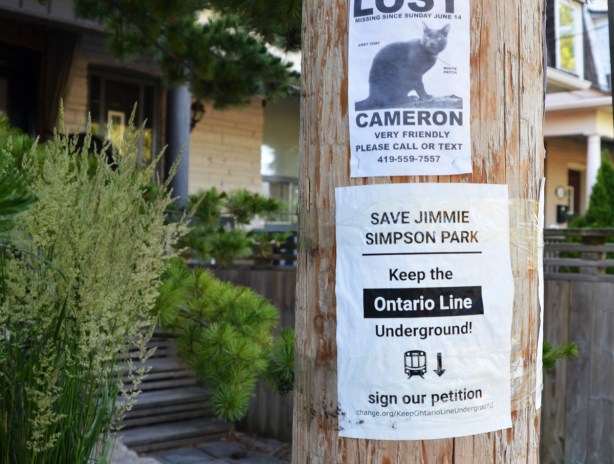 posters on a wood utility pole, bottom is to protest Ontario Line (subway) and to keep it underground and not run it through Jimmie Simpson parl. upper poster is for a lost cat