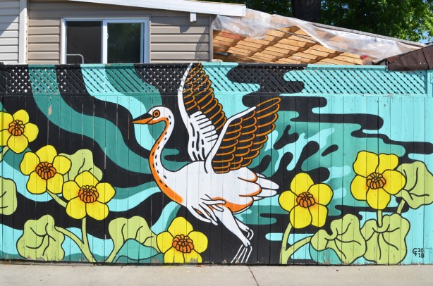 mural of a large white bird, swan?, heron?, stork?, with wings in position as if about to fly, large yellow flowers 