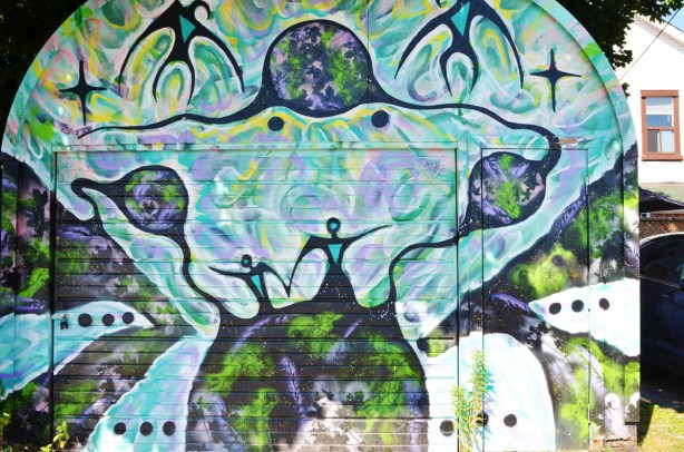 mural on a garage door of purplish figures, looks very first nations-like