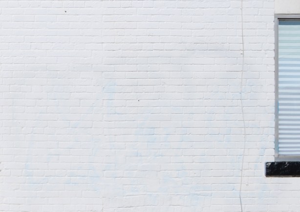 white brick wall with part of a window with white blinds
