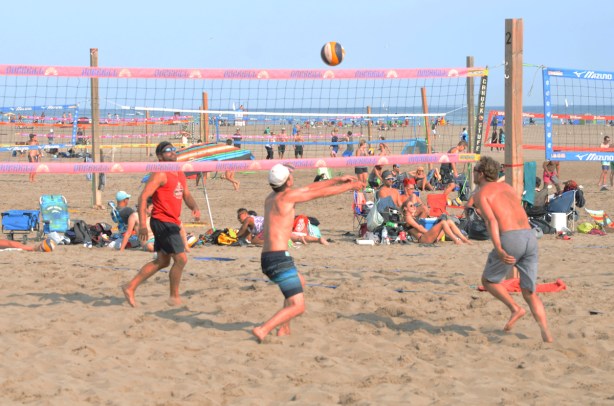young people playing volleyball on the beach in the sane 
