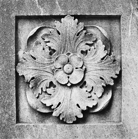 a carving in stone, square panel with a 4 petal flower with 4 leaves, symmetrical