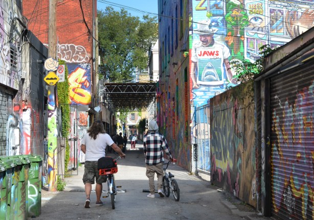 two young men walking their bikes down Graffiti Alley 