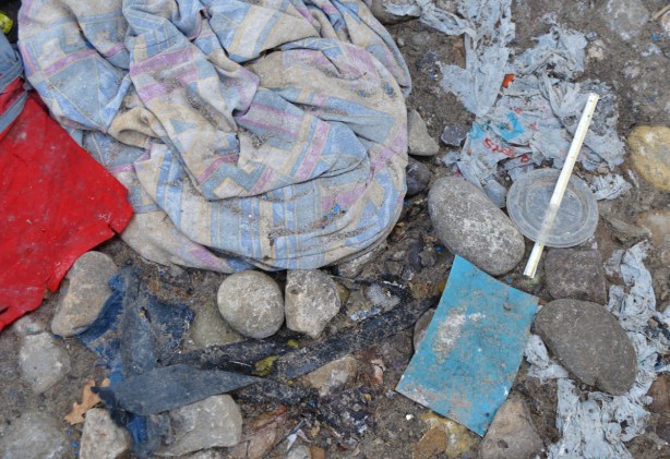 old clothing discarded and left on the ground, also a straw and a plastic lid