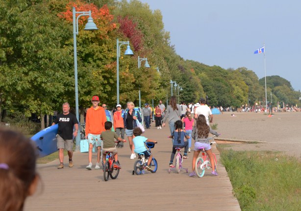 people walking on the boardwalk at Toronto waterfront, including four kids on their bikes, four aside, blocking traffic 