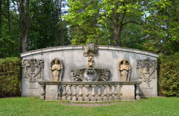 small concrete wall that incorporates a number of small sculptures from old buildings