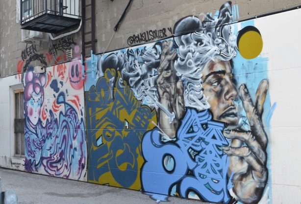 two murals on the side of a building in a small alley in North York 