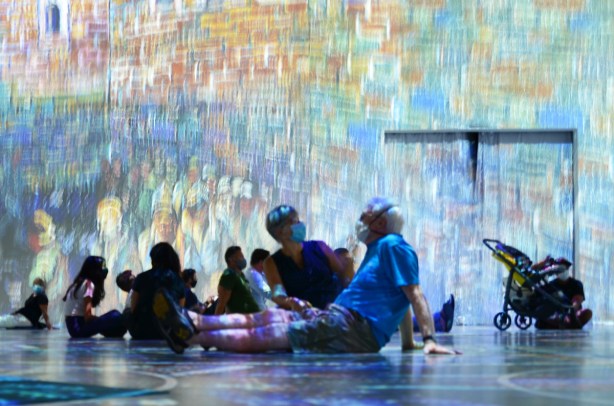 Vincent Van Gogh Immersive exhibit - a middle aged couple sitting on floor, a baby stroller sitting by the exit 