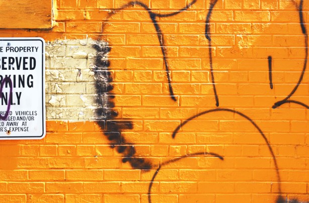 brick wall painted orange with graffiti on it 