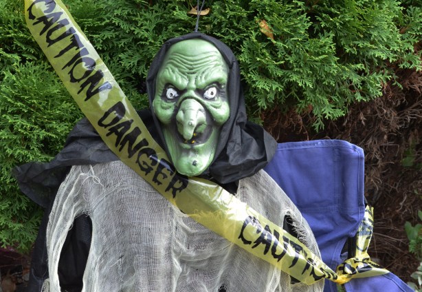 yellow caution danger tape crosses in front of a green ugly mask on a white cloth