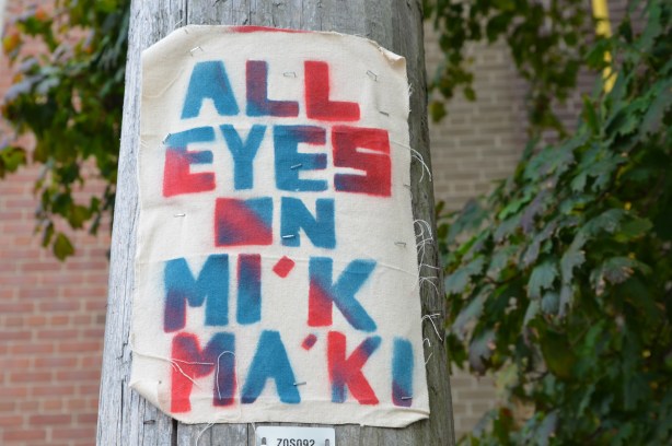 on a wood utility pole, a poster made of fabric that says All Eyes on Mi'kma'ki
