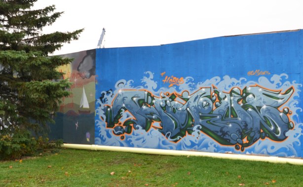 wildstyle mural on blue hoardings, pine tree beside