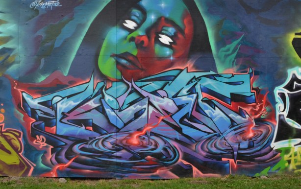  water treatment facility construction hoardings, mural, by kizmet 32, a woman's face in green, blue and red, on top of a textual 
