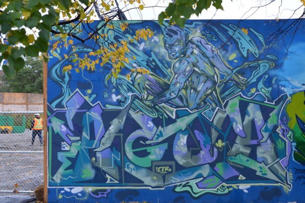 mural on hoardings near Ashbridge Bay water treatment facility, blues wildstyle with man that looks like he's made of water, on a skateboard 