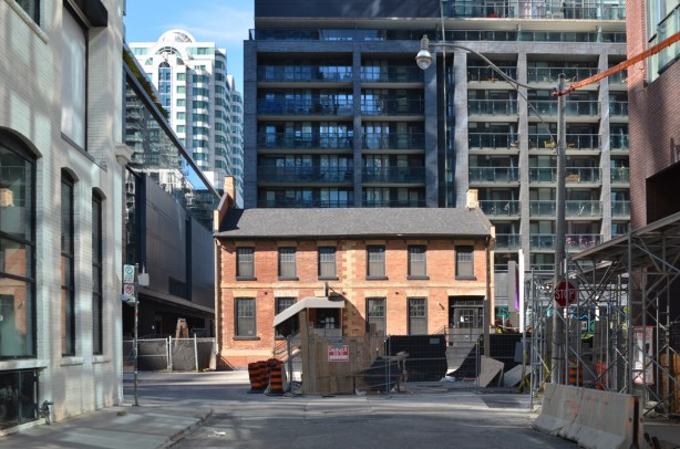 old red brick building being preserved in downtown Toronto, with newer taller buildings surrounding it 