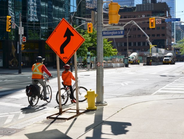 mother and daughter in orange jackets on bicycles, stopped at a red light 