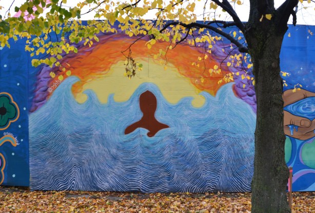 mural on hoardings near Ashbridge Bay water treatment facility, brown profile in water near yellow and orange shore