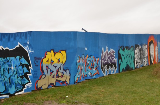 on blue hoardings, a row of text graffiti