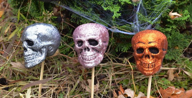shiny glittery small skulls in a line in a garden