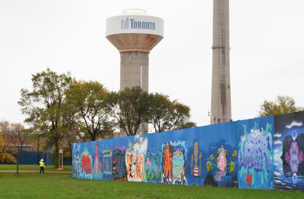 city of toronto concrete water tower behind blue hoardings with street art murals on them 