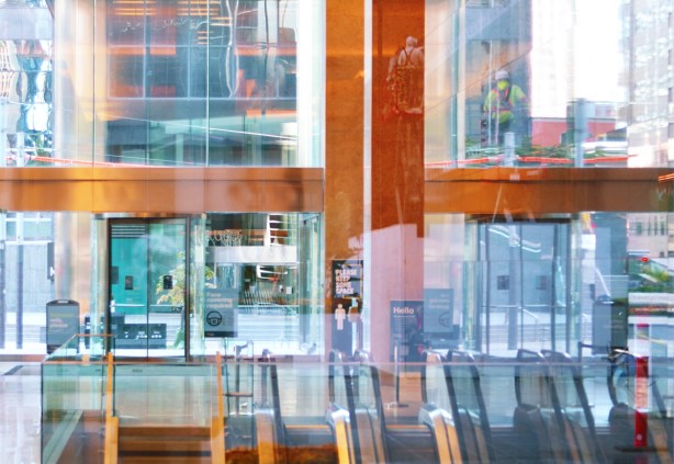 window washers and reflections, looking through a glass building from back to ftont, escalators down, high ceiling, 