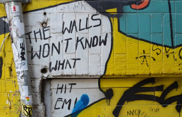 part of a mural on a wall, words that say the walls won't know what hit them. 